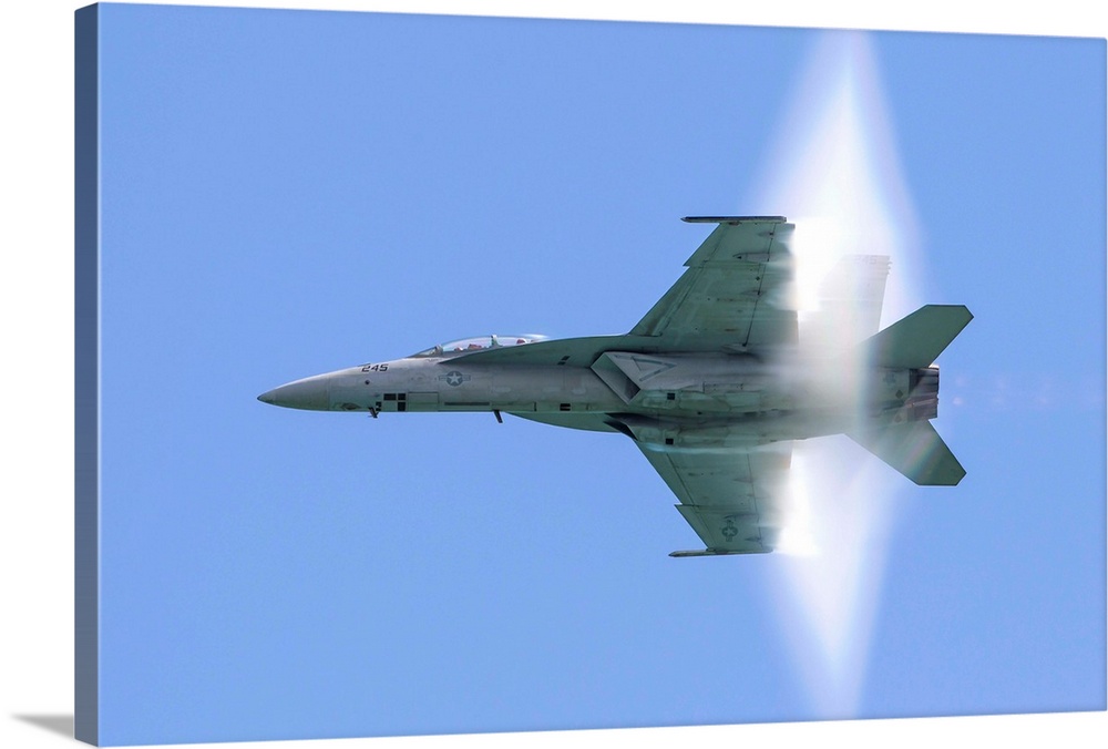 A U.S. Navy F/A-18F Super Hornet flies by at high transonic speed.