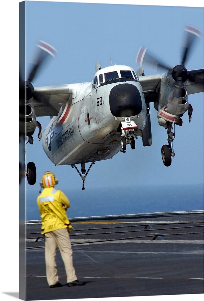 A US Navy officer observes a C2A Greyhound aircraft landing onboard USS Harry S Truman