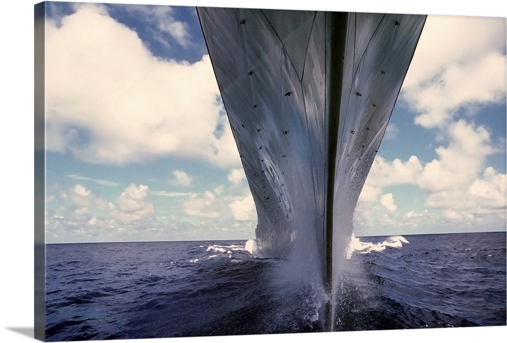 Landscape, close up photograph of the bow of the battleship USS Missouri, taken at water level as it charges forward throu...