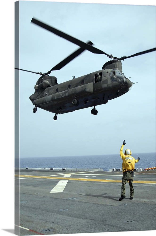 Airman directs an Army CH-47 Chinook helicopter on the flight deck.