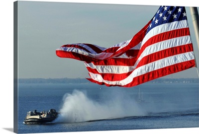 American flag blowing in the wind with a hovercraft in the background