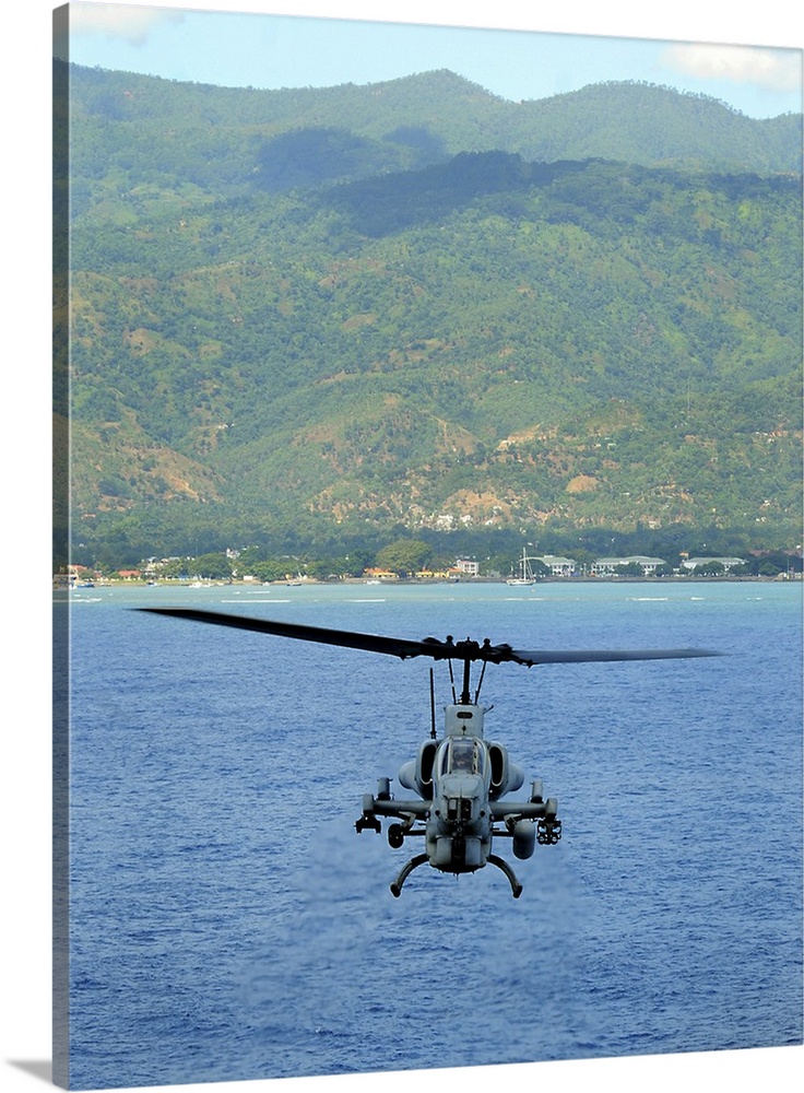 An AH-1W Super Cobra flies off the coast of Dili, East Timor.