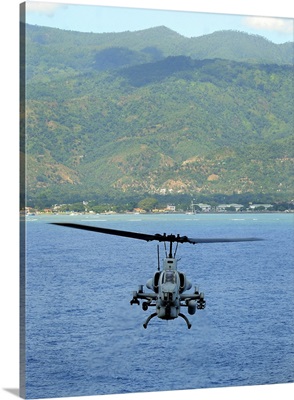 An AH-1W Super Cobra flies off the coast of Dili, East Timor