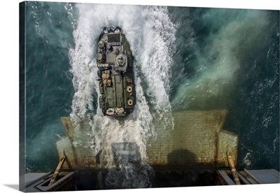 An amphibious assault vehicle exits the well deck of USS Bataan