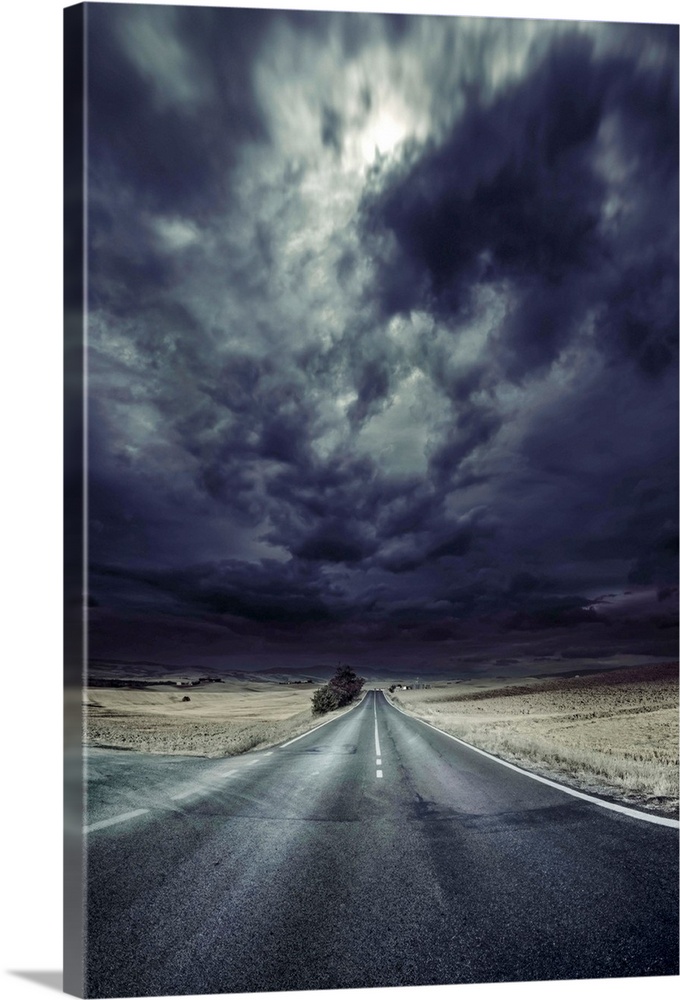 An asphalt road with stormy sky above, Tuscany, Italy.