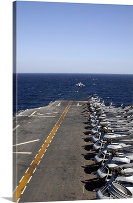 An AV-8B takes off from the flight deck of USS Tarawa lined with helicopters