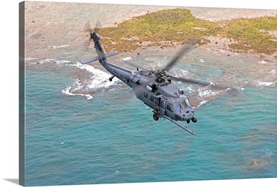 An HH-60G Pave Hawk flies along the coastline of Okinawa, Japan