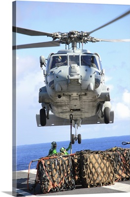An HH-60H Sea Hawk helicopter picks up supplies from the flight deck