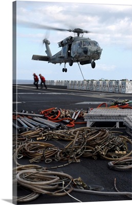 An HH-60H Seahawk helicopter prepares to lift a crate of ordnance
