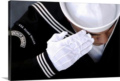 An Honor Guard member renders a salute during a burial at sea ceremony