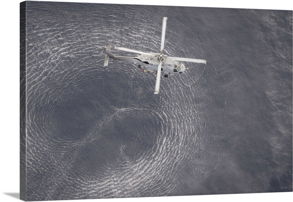 An MH-60R Seahawk helicopter hovers over the Pacific Ocean.