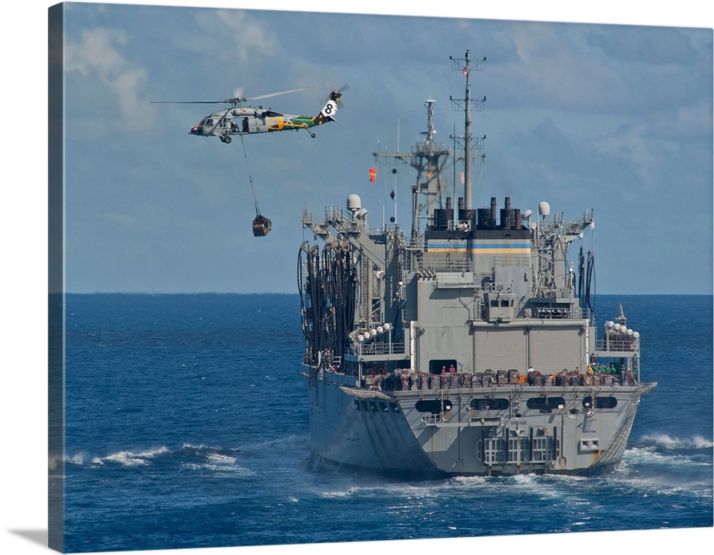 An MH-60S Sea Hawk conducts a vertical replenishment with USNS Bridge.