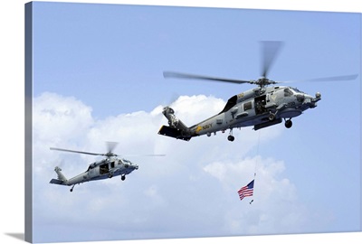 An MH-60S Sea Hawk helicopter follows behind an MH-60R Sea Hawk