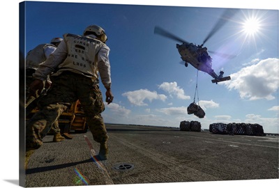 An MH-60S Sea Hawk helicopter lowers pallets of supplies onto USS Bonhomme Richard