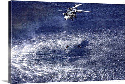 An MH-60S Seahawk lowers a rescue swimmer into the water