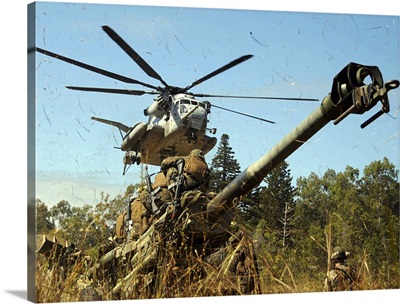 An MH53E Sea Stallion helicopter preparing to lift an M777 105mm lightweight Howitzer