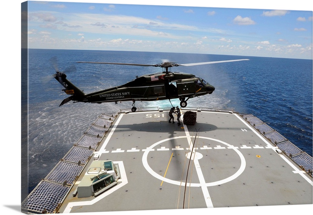 An SH-60F Sea Hawk helicopter lowers pallets onto HMAS Ballarat.