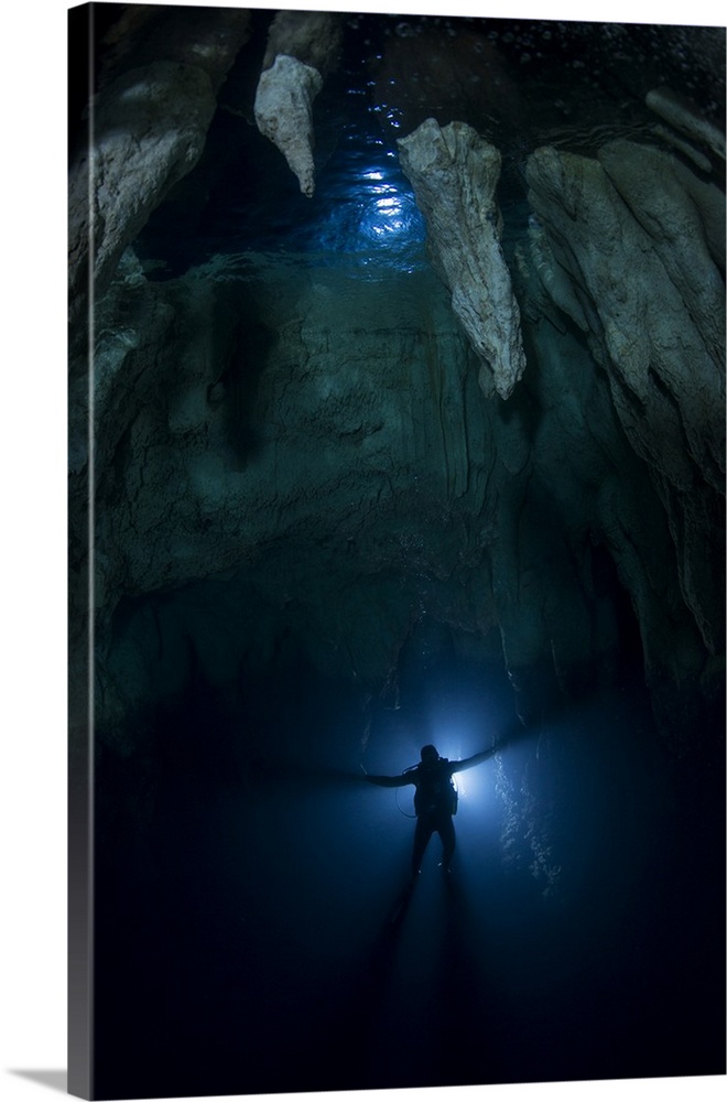 Backlit diver in Chandelier Cave with large stalactites.