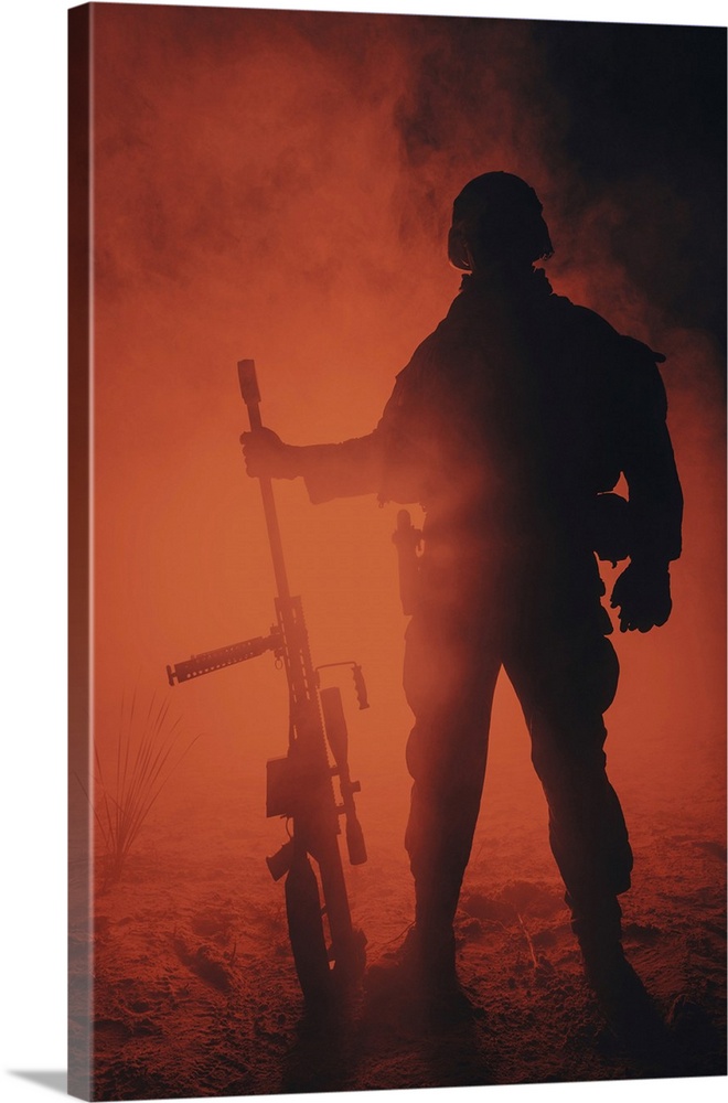 Backlit silhouette of Army sniper with large caliber rifle standing in the fire and smoke.