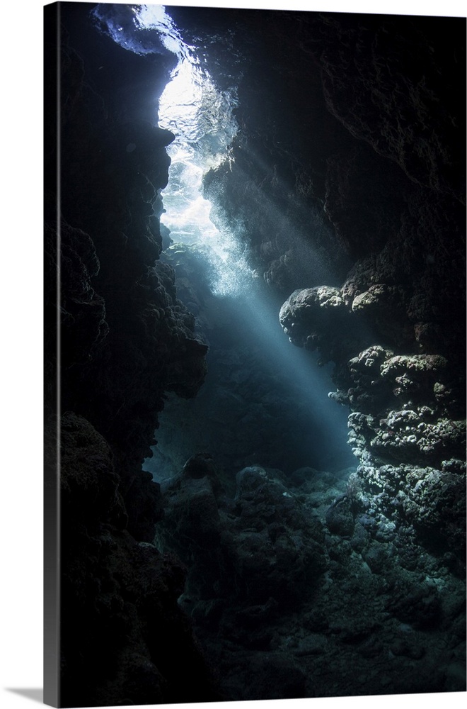 Beams of light descend into the darkness of a cavern in the Solomon Islands.