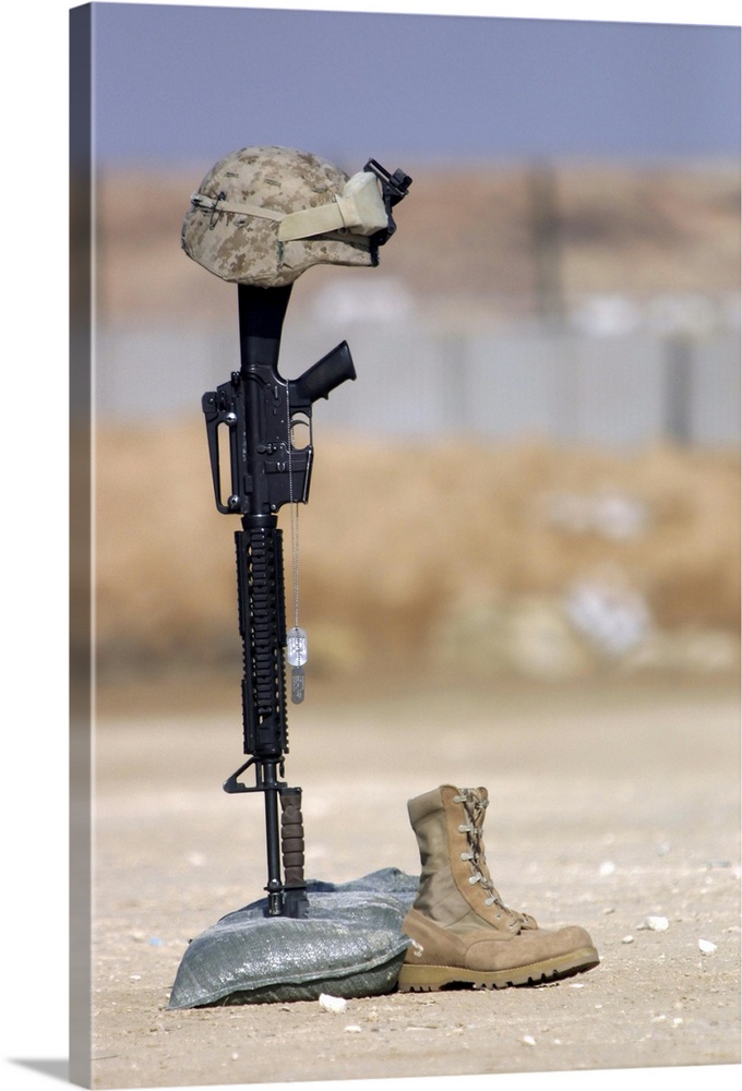 Boots, rifle, dog tags, and protective helmet stand in solitude to honor fallen soldiers.