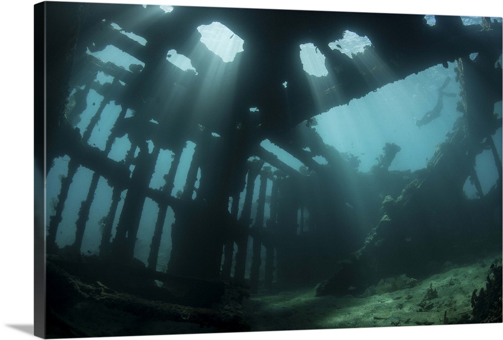 Bright sunlight pierces a shallow World War II shipwreck.