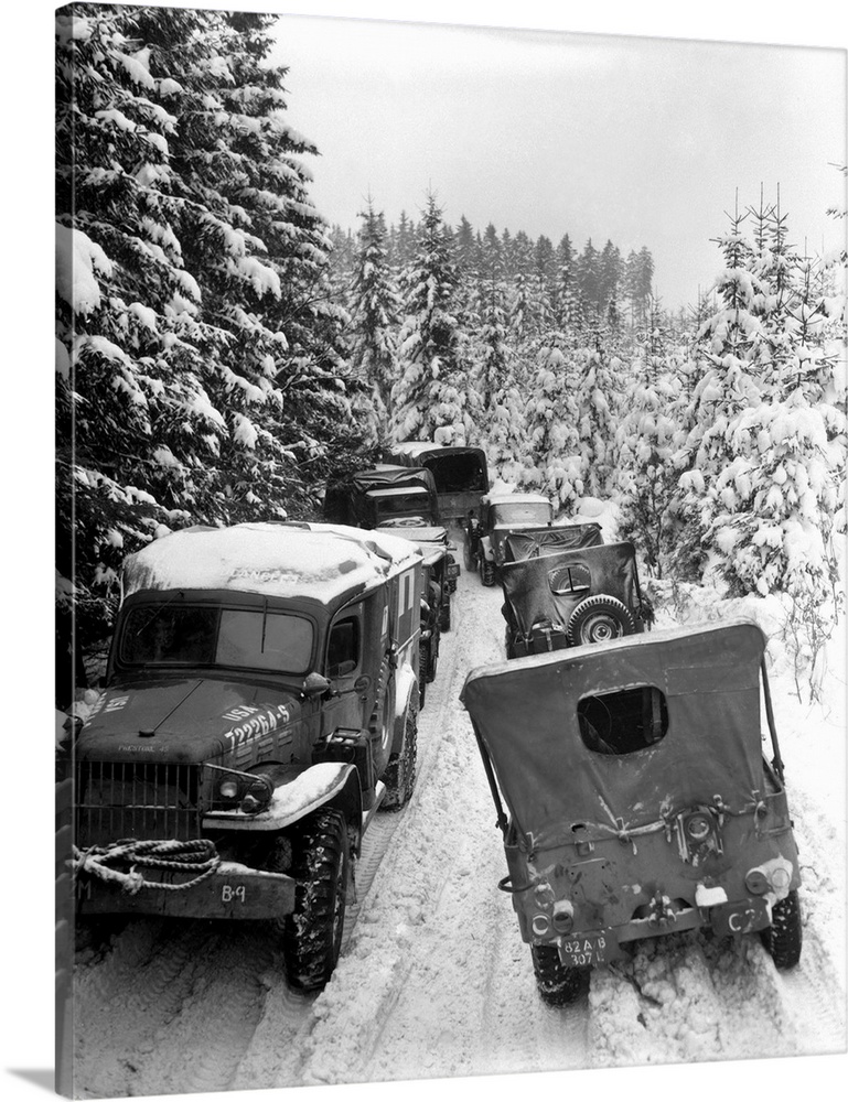 Deep snow banks on a narrow road halt military vehicles in Belgium, 1945.