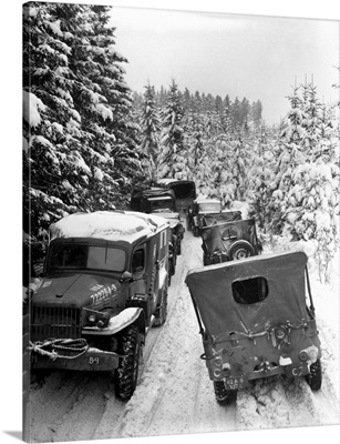 Deep snow banks on a narrow road halt military vehicles in Belgium