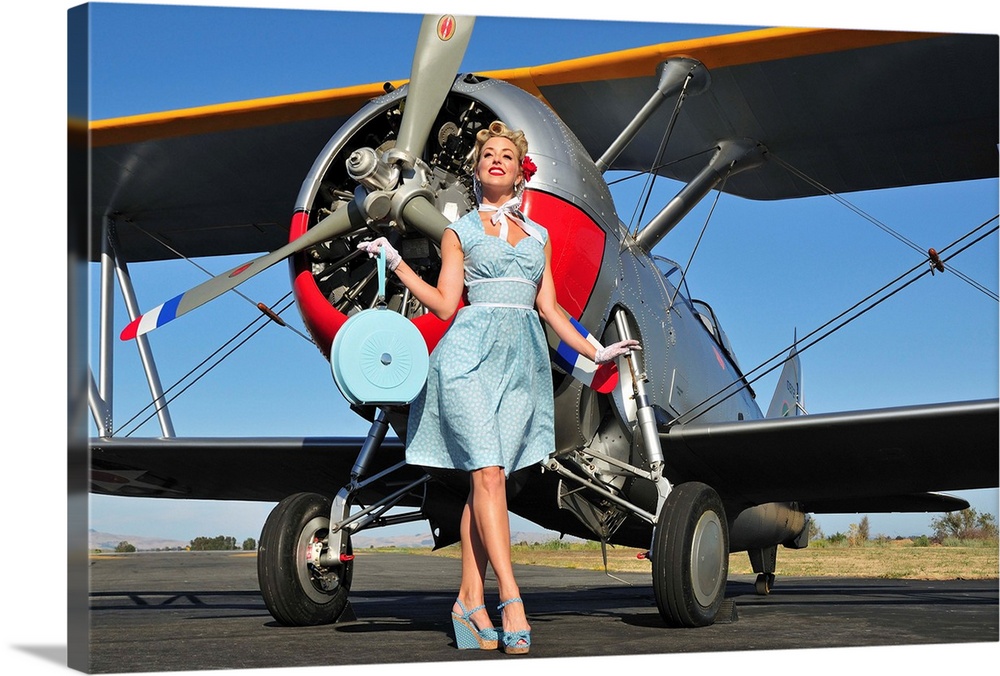 Elegant 1940's style pin-up girl standing in front of an F3F biplane.