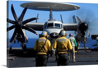 Flight deck directors watch as pilots of an E2C Hawkeye startup their engines