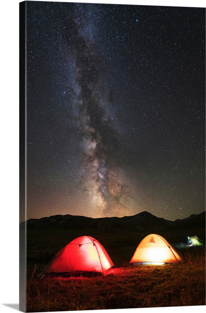 Glowing tents under the Milky Way in the mountains of Russia.