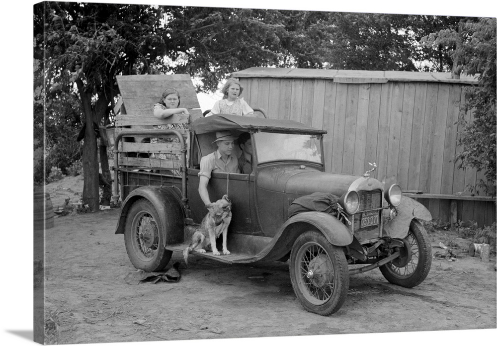 Great Depression era photograph of a migrant family in a packed car preparing to leave.