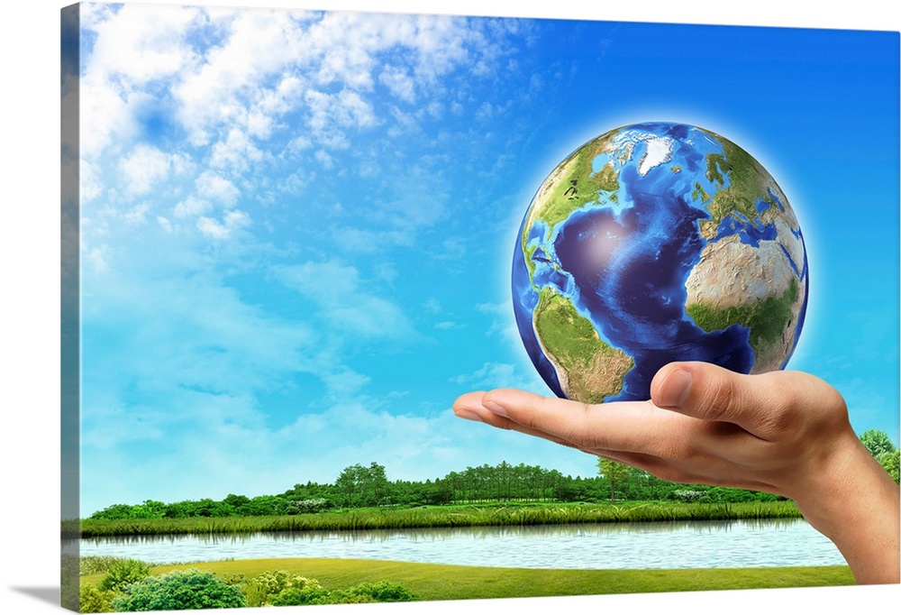 Human hand holding Earth globe with a green landscape background.