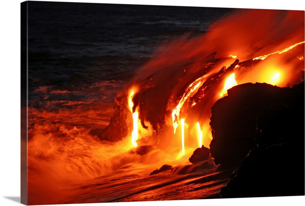 Photograph of magma running off a rock into the ocean at night.