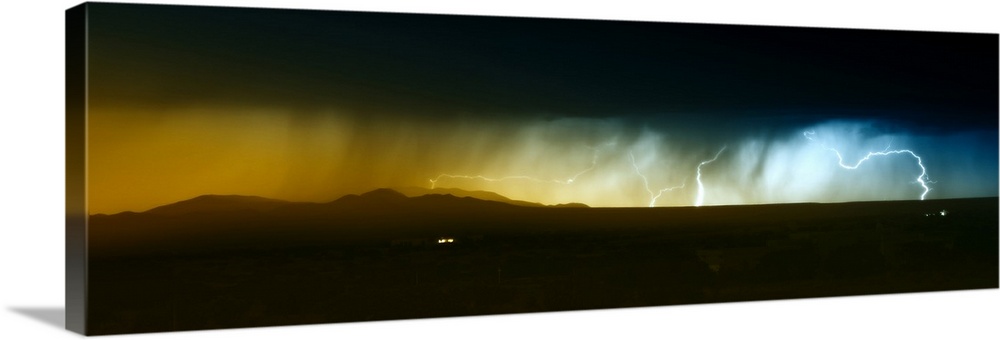 Dramatic panoramic photograph of a heavy rainstorm with bolts of lightning passing over the Southwest desert.