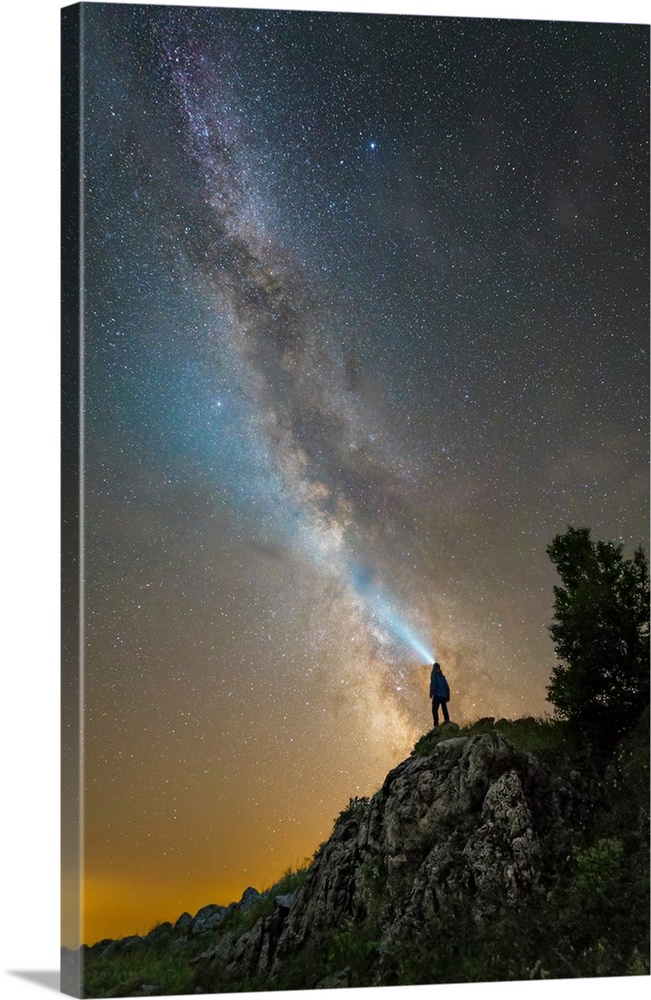 Man shining a flashlight on the Milky Way from atop a mountain in Russia.