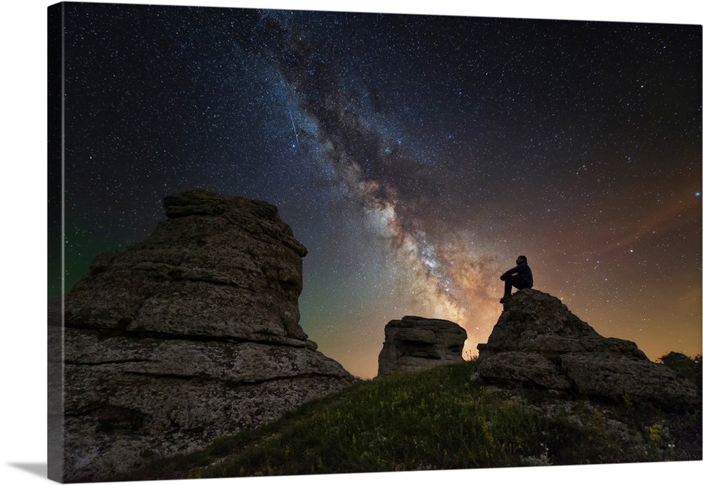 Man sits on top of Demerdzhi mountain under the Milky Way at night.