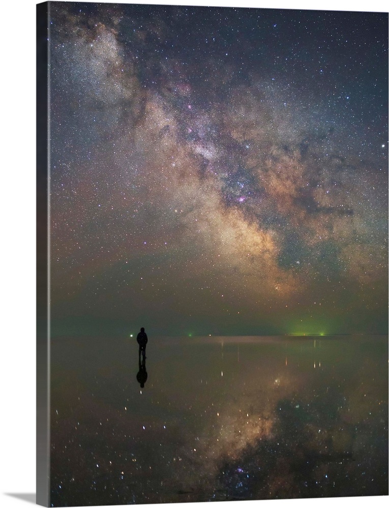 Man stands alone on Lake Elton in Russia under the center of the Milky Way.