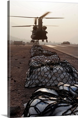 Marines attach sling loads to the body of an Army CH47 Chinook cargo helicopter