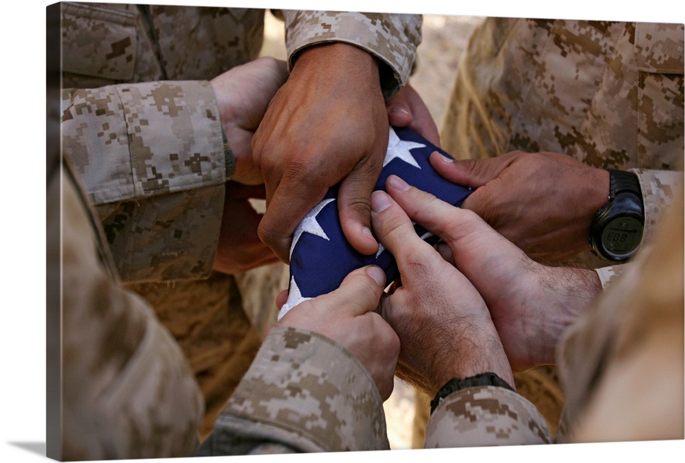 Photograph of soldiers' hands holding star covered fabric.