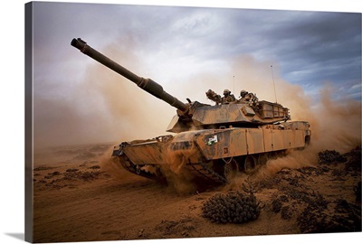 Marines roll down a dirt road on their M1A1 Abrams Main Battle Tank