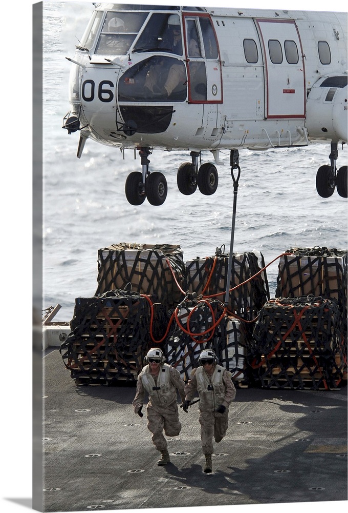 Marines run out from under an SA-330J Puma after hooking it to cargo.