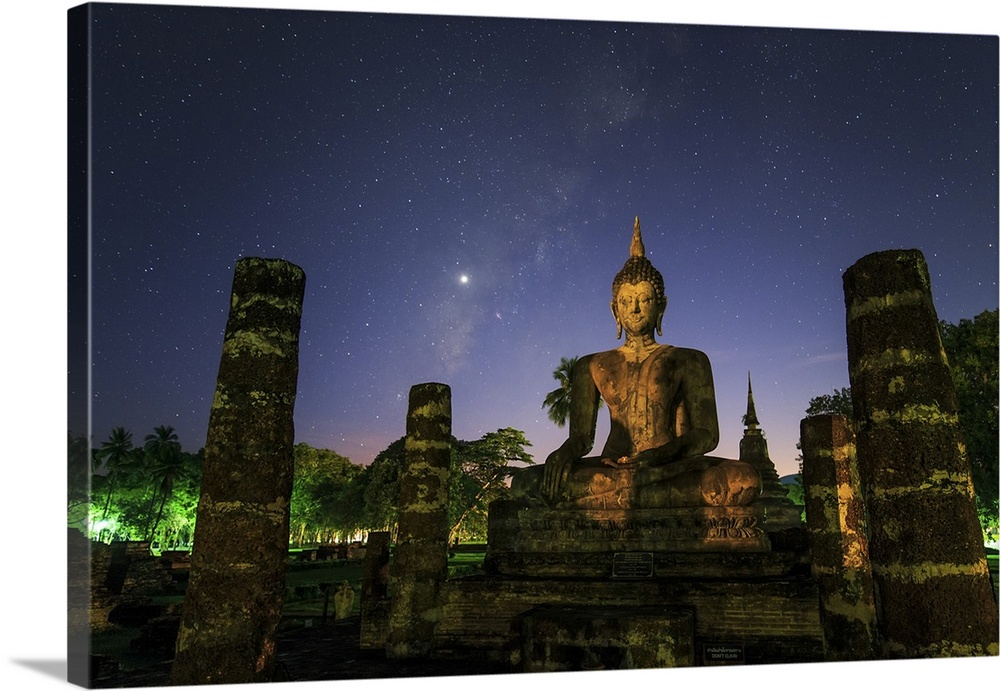 The Milky way and Venus shine in the evening twilight above a buddha in Sukhothai, Thailand.