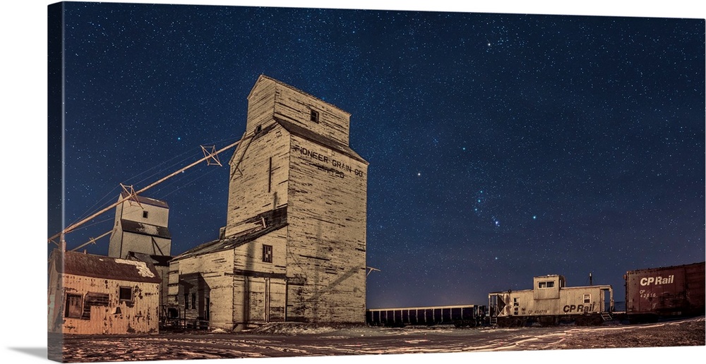 Orion and the winter stars rising behind grain elevators in Mossleigh, Canada.
