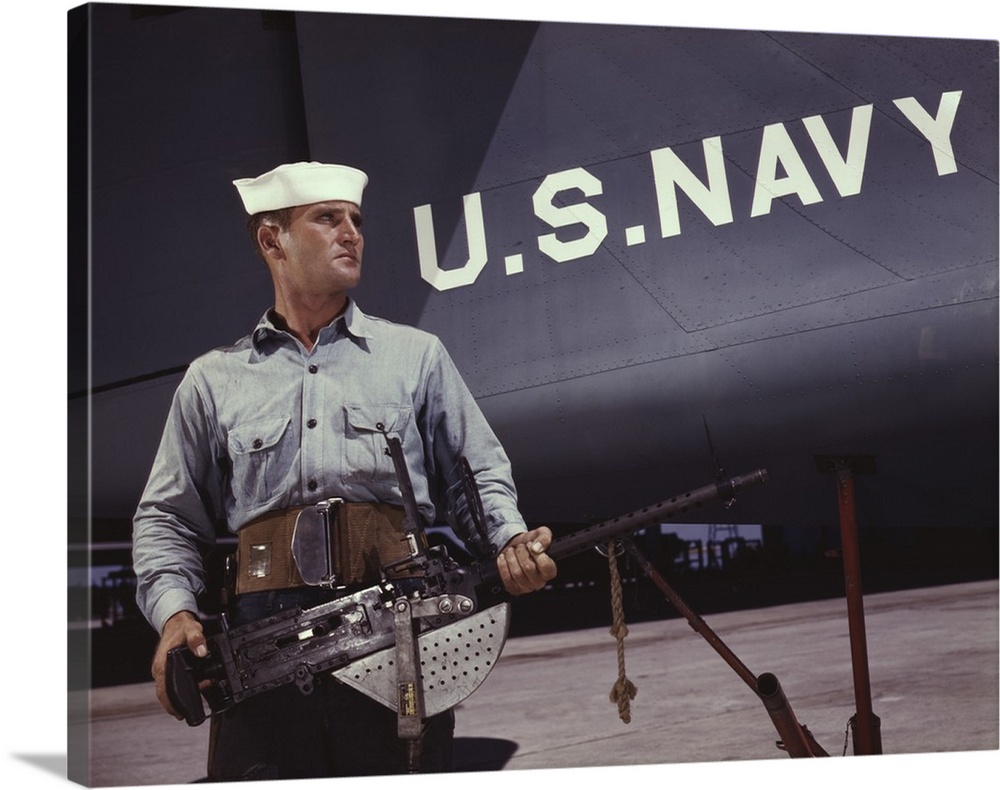 August 1942 - Sailor holding a .30-caliber machine gun in front of a U.S. Navy plane at Naval Air Base, Corpus Christi, Te...