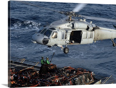Sailors attach pallets of supplies to an MH-60S Knighthawk