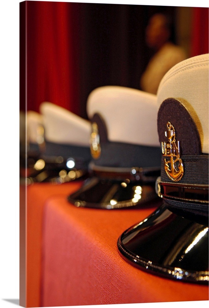 Several chief petty officers combination covers lined up on a table