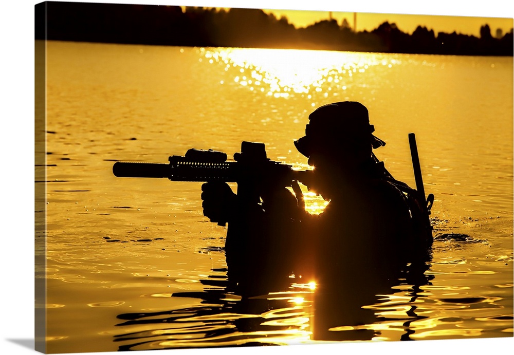 Silhouette of a special forces soldier with rifle, crossing a river in the jungle.