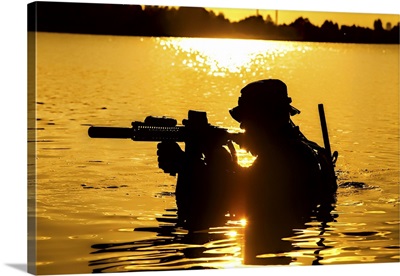 Silhouette Of A Special Forces Soldier With Rifle, Crossing A River In The Jungle