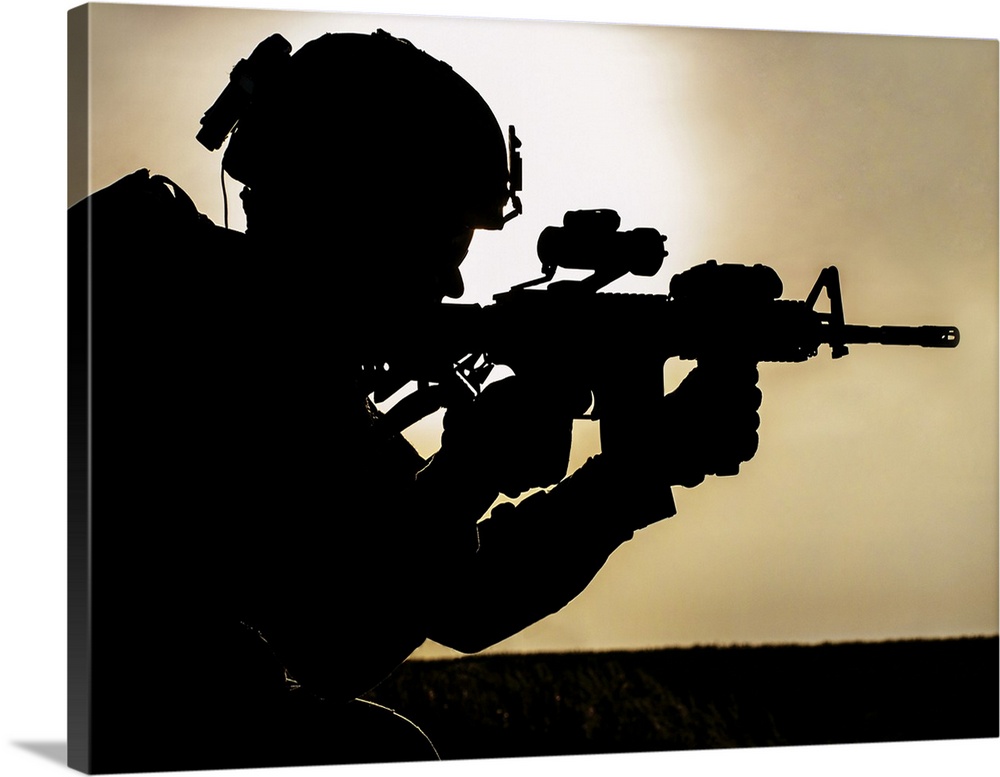 Silhouette of young soldier in military helmet against the sun.